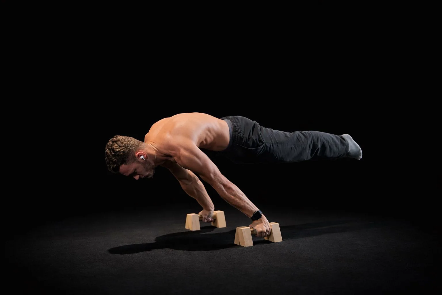Sjakie, online calisthenics coach, holding a planche on wooden parallettes